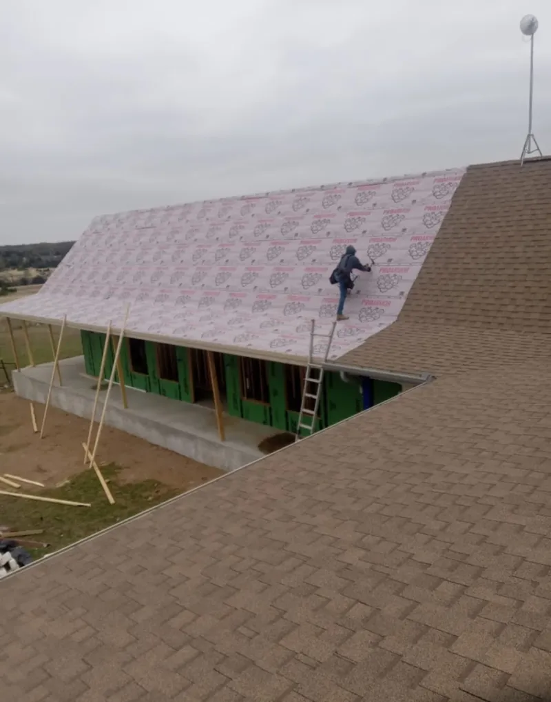 Worker preparing underlayment for a metal roof installation in Waldorf